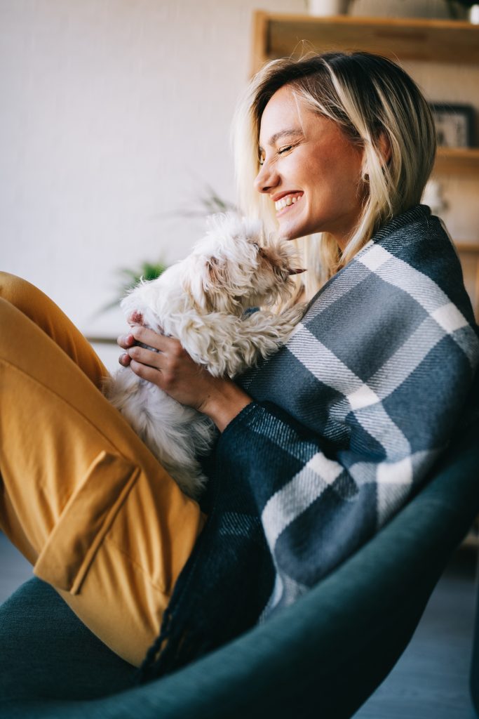 Small dog sitting in woman's lap on sofa.